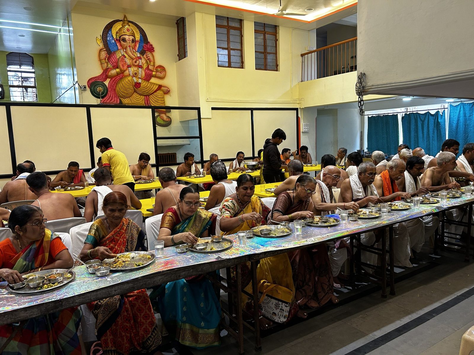 Guests enjoying a meal at long tables during a function in a hall
