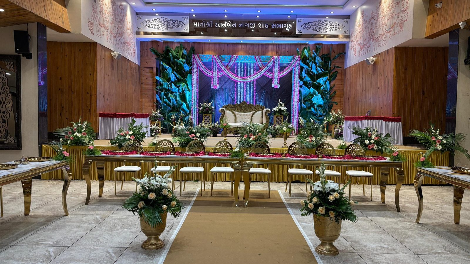 Banquet hall laid out for a function, with dining tables and a decorated stage