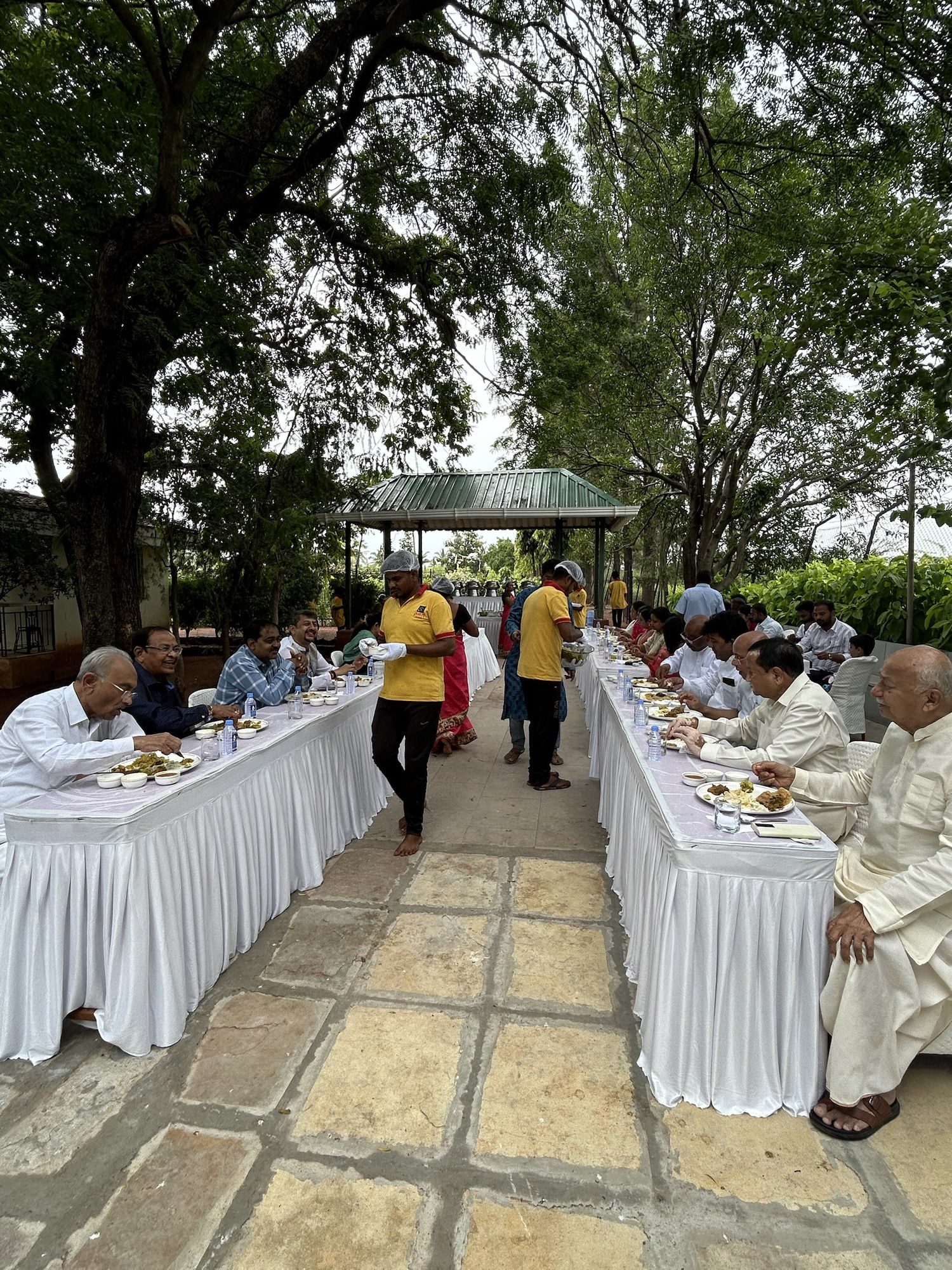 An outdoor pangat under the trees, with guests being served at long tables