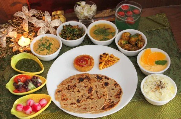 A festive vegetarian thali with paratha, curries, chutneys, salad and sweets